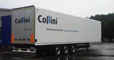 Auf dem Bild ist ein Schiebebügelverdeck vom Fabrikat Edscha für die Firma Collini zu sehen. Die Plane ist weiß und trägt eine auffällige Beschriftung, die auf die Firma Collini hinweist.